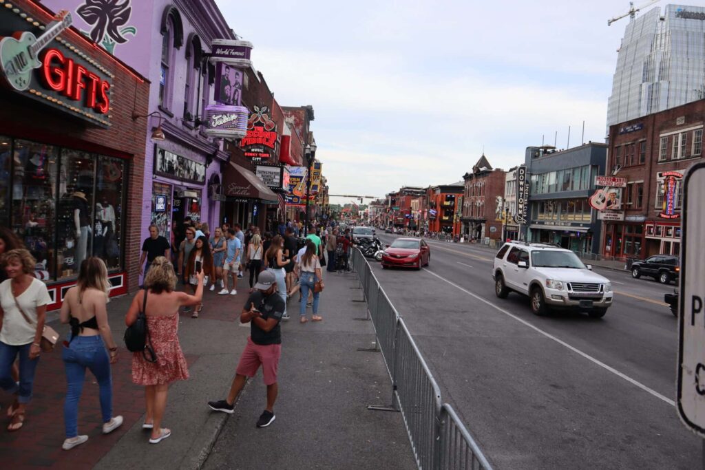 Vibrant street scene in downtown Nashville, Tennessee, showcasing Broadway's bustling atmosphere with pedestrians, vehicles, and