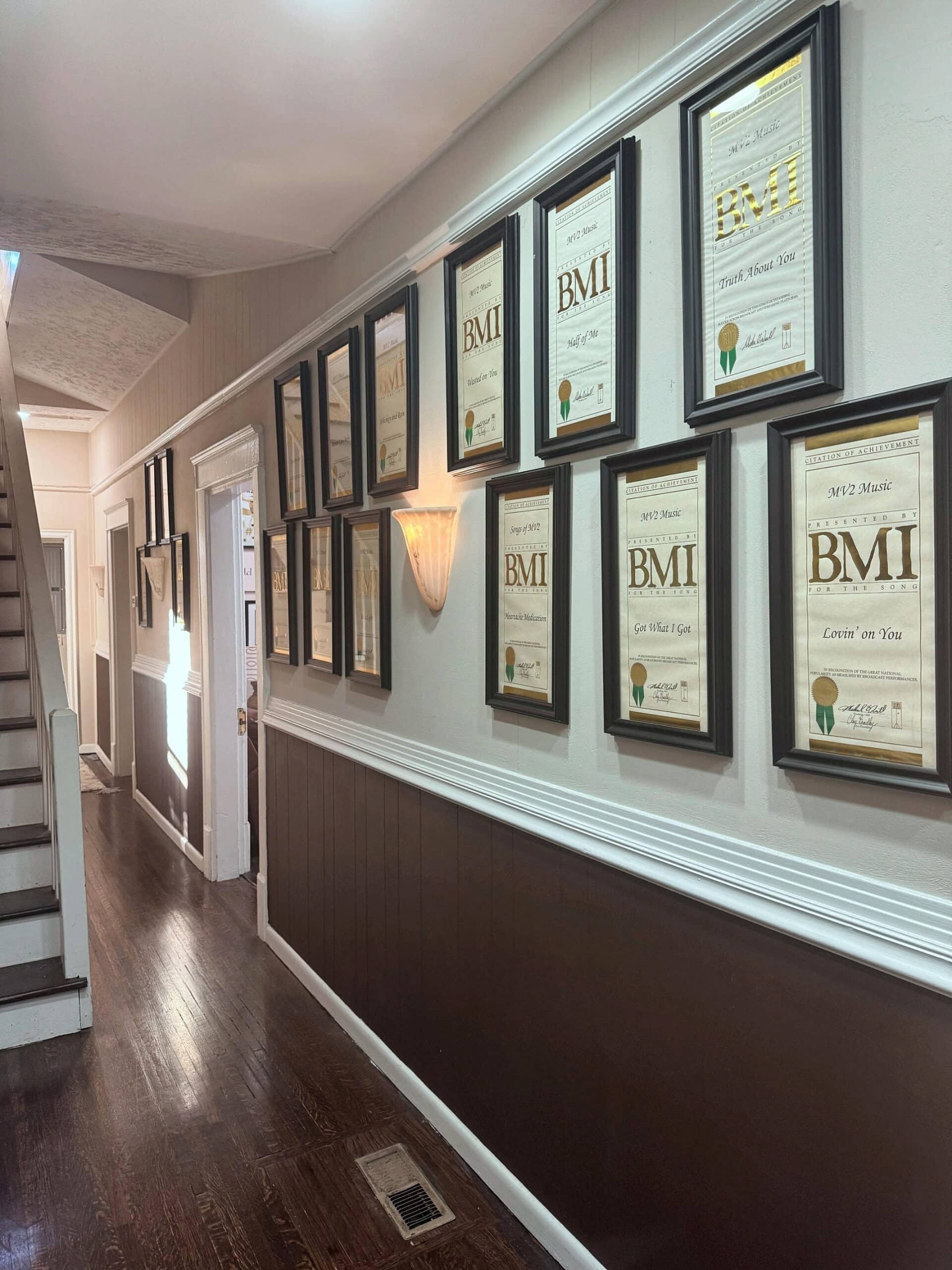 Recording studio wall showing BMI records in frames along the hallway wall